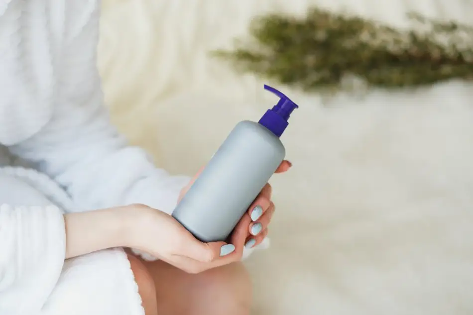 bouteille de shampoing tenue par une femme en peignoir